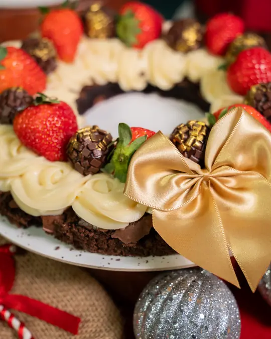 Guirlanda brownie de Natal com rosetas de creme, morangos e laço dourado