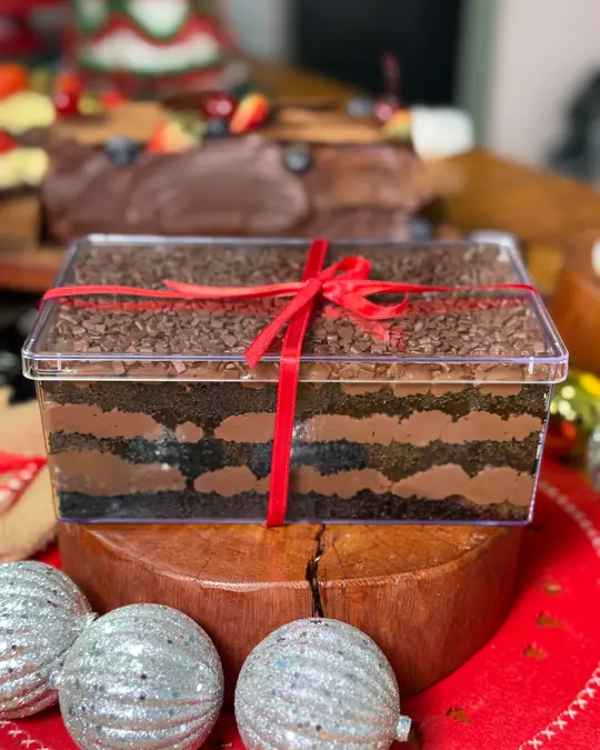 Matilda Cake na travessa de acetato, com camadas de chocolate e laço de fita vermelha