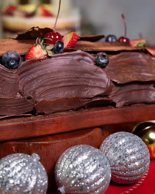 Rocambole trufado de chocolate decorado com cerejas e frutas vermelhas